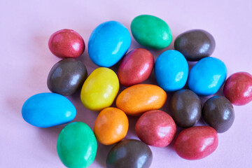 Colorful chocolate candies on pastel pink background. Top view.