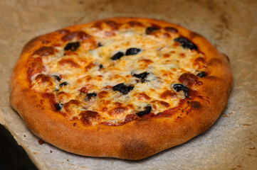 Delicious homemade pizza topped with olives, bubbling cheese, and golden crust, freshly baked in a cozy kitchen