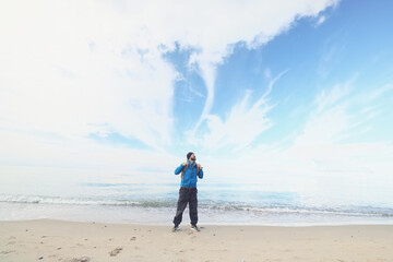 A guy with a backpack against the blue sky on the coast