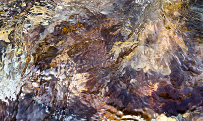 dynamic abstract water texture with rich earthy tones and soft distortions over rocky shore. deep visual texture of artistic water