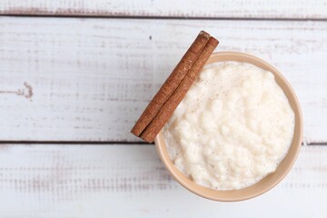 Tasty rice pudding with cinnamon on white wooden table, top view. Space for text