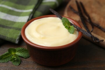 Tasty vanilla pudding, mint and pods on wooden table, closeup