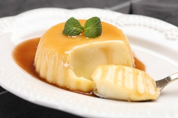 Delicious pudding with caramel sauce and mint served on table, closeup
