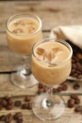 Coffee cream liqueur in glasses and beans on table, closeup