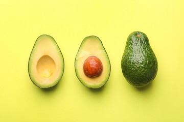 Whole and cut avocados on light green background, flat lay