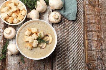 Delicious mushroom cream soup with croutons, dill and ingredients on wooden table, flat lay. Space for text