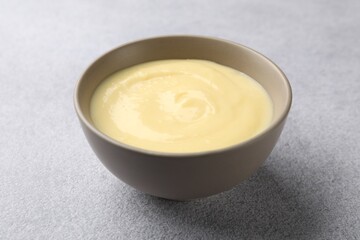 Tasty vanilla pudding in bowl on light grey table, closeup