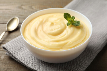 Tasty vanilla pudding with mint served on wooden table, closeup