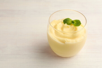 Tasty vanilla pudding with mint on white wooden table, closeup. Space for text