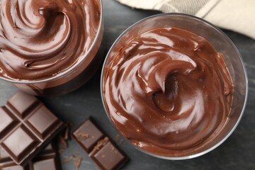 Tasty pudding and pieces of chocolate on grey table, flat lay