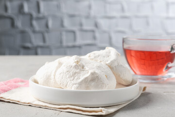Delicious homemade meringue cookies and tea on gray table, closeup
