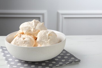 Delicious homemade meringue cookies in bowl on light table, space for text