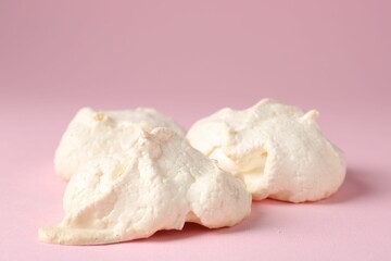 Delicious homemade meringue cookies on pink background, closeup