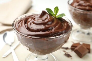 Delicious chocolate pudding with mint in dessert bowl on white table, closeup