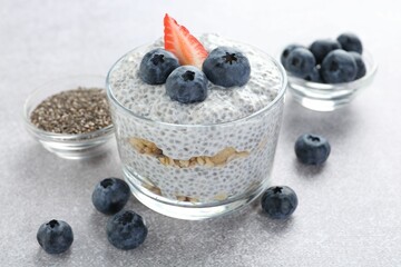 Delicious pudding with chia seeds, yogurt, blueberries, granola and strawberry on light grey table, closeup. Superfood