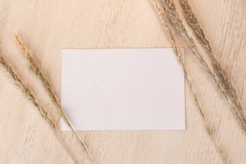 White blank business card mockup with dried flower on brown background