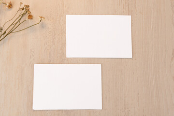White blank business card mockup with dried flower on brown background