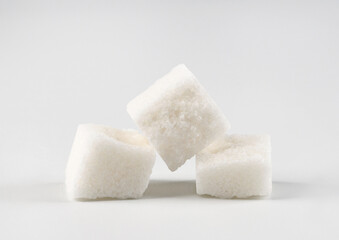 Three pieces of white granulated sugar on a white background. White on white.