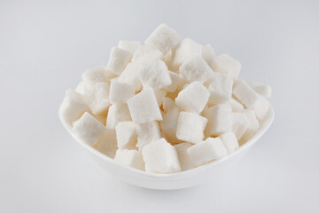 White plate with pieces of crushed white sugar on a white background. Sugar in pieces.