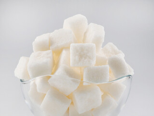 White sugar in a glass sugar bowl on a white background. Sugar in pieces.