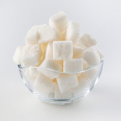 White sugar in a glass sugar bowl on a white background. Sugar in pieces.