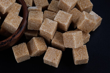 Brown sugar cubes on black background, top view. Cane brown sugar.