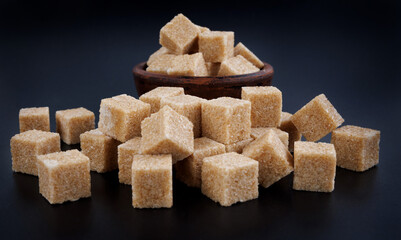 Cane brown sugar on a black background. Sugar cubes.
