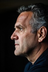 Fototapeta premium Contemplative Mature Man in Profile Against Dark Background - Thoughtful Portrait.