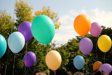 Bright colorful balloons floating in the sky during a festive outdoor event, perfect for graduation, school celebration or children’s day