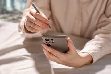 Hands holding phone and writing with stylus on phone. Close-up.