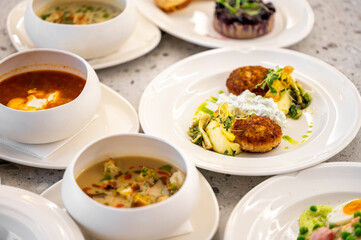 A beautifully arranged table featuring various dishes, including soups and plates with crispy patties, garnished with fresh herbs, highlighting an elegant dining experience.