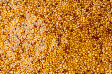 French Dijon mustard in a metal spoon, top view on mustard grains background. Gastronomy concept, organic food. Sauce. 