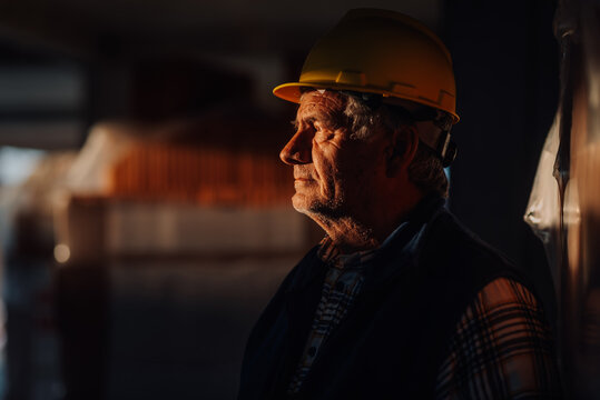 Senior construction worker wearing hard hat inspecting warehouse