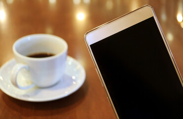 Closeup of Blank Screen Mobile Phone with Blurry Black Coffee in the Backdrop