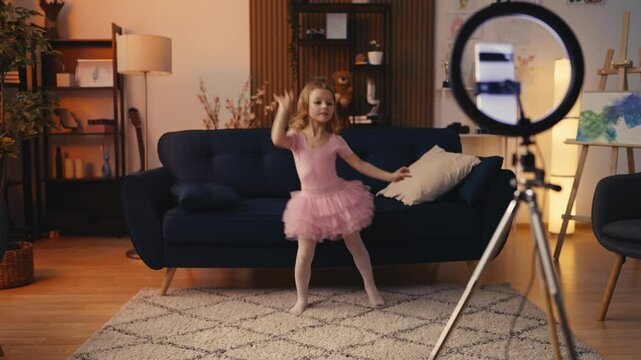 Adorable little girl in ballet tutu dress recording dance video for social media