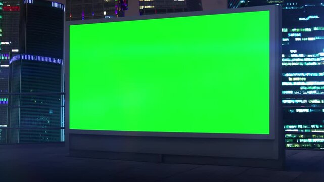Green screen billboard on building roof with cityscape at night