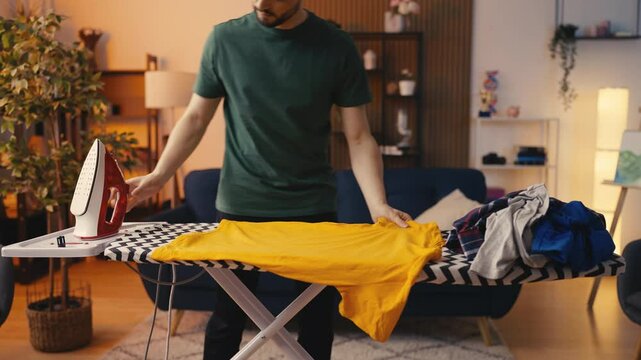 Young male carefully ironing clothes, meticulous man doing household chores