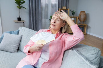 Mid aged woman suffering from heat and fanning herself