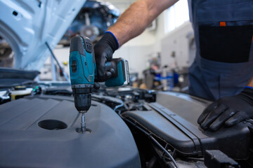 Bearded male technician in shop doing diagnostics and vehicle maintenance