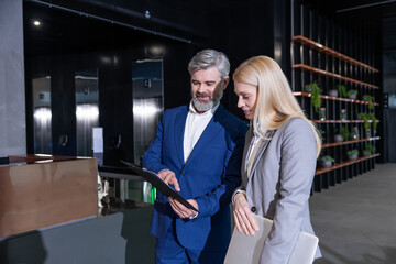 Businesswoman and manager standing in office corridor discussing company development