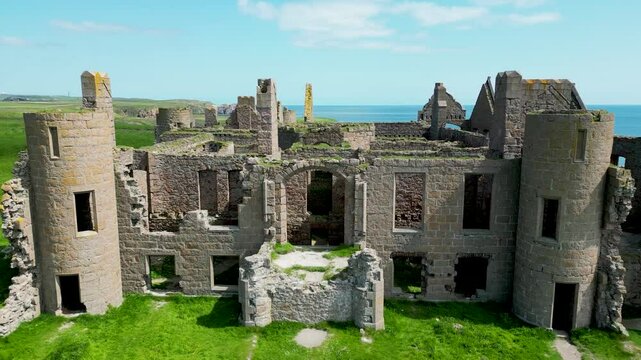 Drone scenic view of the Slain's Castle ruins on a green land overlooking ocean in Aberdeenshire