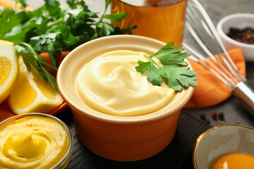 Delicious mayonnaise sauce in bowl and ingredients on grey table, closeup
