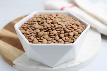 Raw brown lentils on white table, closeup