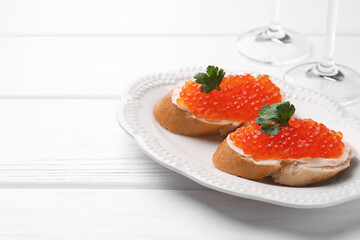 Tasty sandwiches with red caviar on white wooden table, closeup. Space for text
