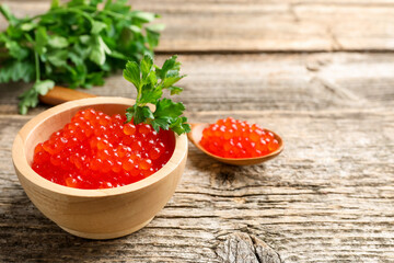 Red caviar and parsley on wooden table, closeup. Space for text