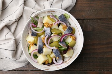 Delicious salad with herring, vegetables and mustard in bowl on wooden table, top view