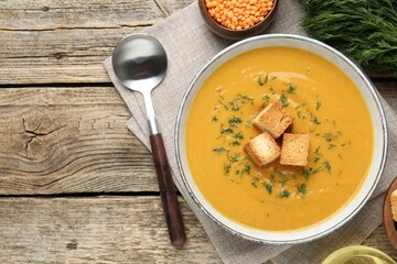 Delicious lentil cream soup served on wooden table, flat lay
