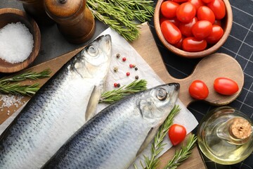 Salted herrings, spices and tomatoes on grey table, flat lay