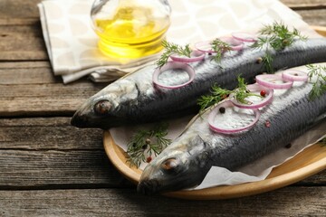 Tasty herrings with spices on wooden table, closeup