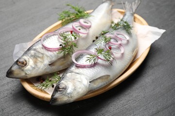 Tasty herrings with spices on black table, closeup